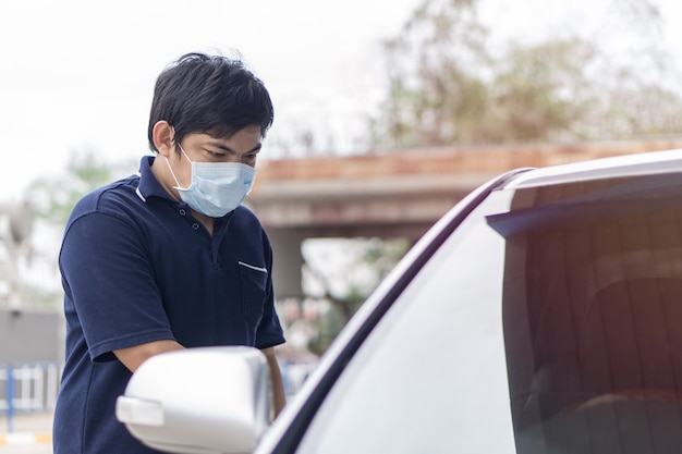 Robber and the car thief in a mask opens the door of the car\
and hijacks the car.