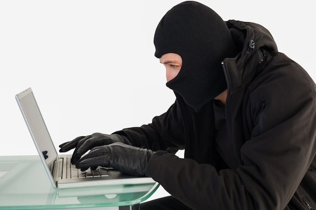 Robber sitting at desk hacking a laptop 