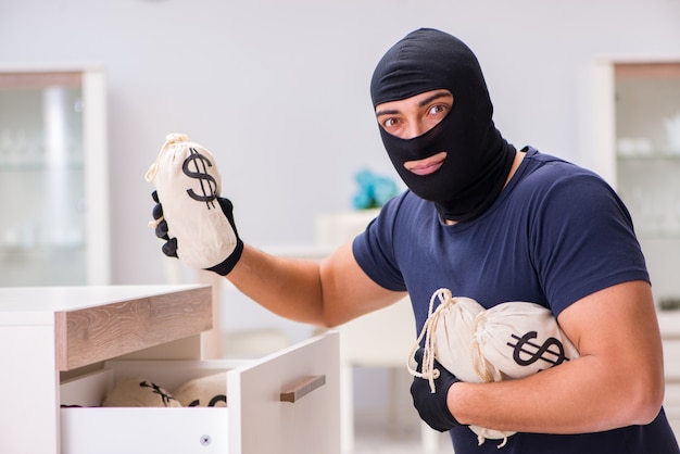 Robber wearing balaclava stealing valuable things