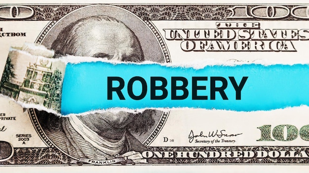 Robbery The word robbery on dollar usa background Theft and stealing money concept The concept of breaking the law