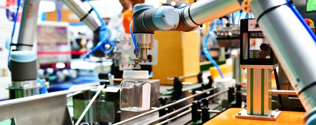 로봇 팔은 생산 라인 공장의 자동 산업 기계 장비에 유리 물병을 배치했습니다.