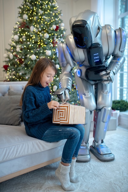 Robot die een kerstcadeau geeft aan een lachend meisje