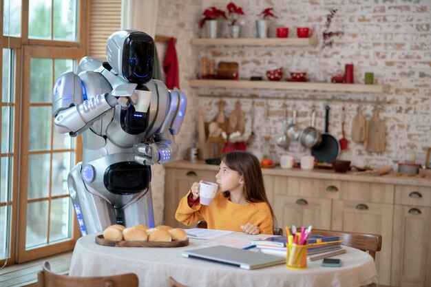 Robot teacher looking attentively how the girl writing