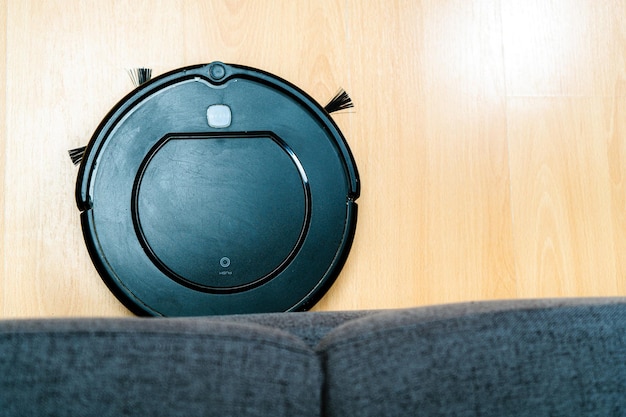 Robot vacuum cleaner cleaning under the sofa. robot vacuum\
cleaner cleaning under the sofa. coming out from under the\
couch.