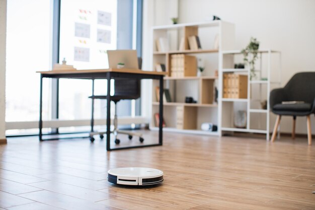 Robot vacuum cleaner handling debris on bare floor in office