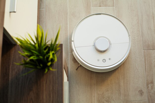 Robot vacuum cleaner performs automatic cleaning of the apartment at a certain time. Smart home.