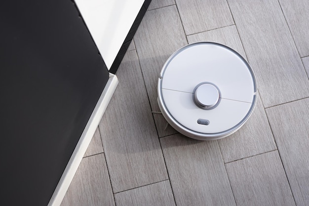 Robot vacuum cleaner removes dust in room on floor. Vacuum cleaner in ordinary apartment. modern household wireless device for cleaning house. smart home concept