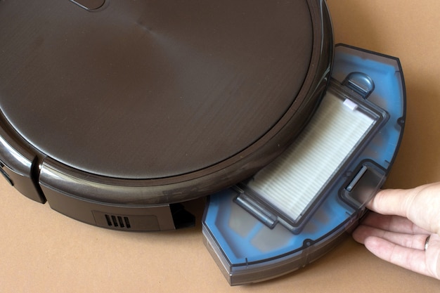 Robot vacuum cleaner replacing a container. Robot vacuum cleaner on brown background. close up.