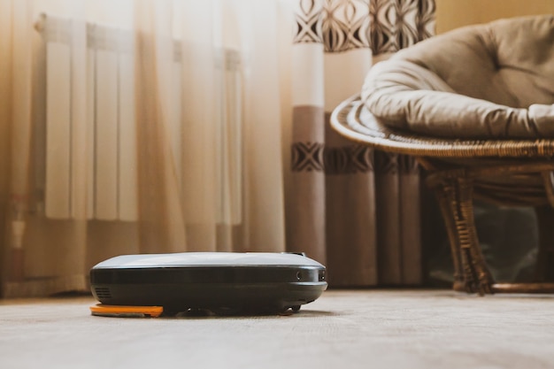 Робот-пылесос в комнате в новой квартире убирает ламинат. Концепция домашних заданий и технологий.