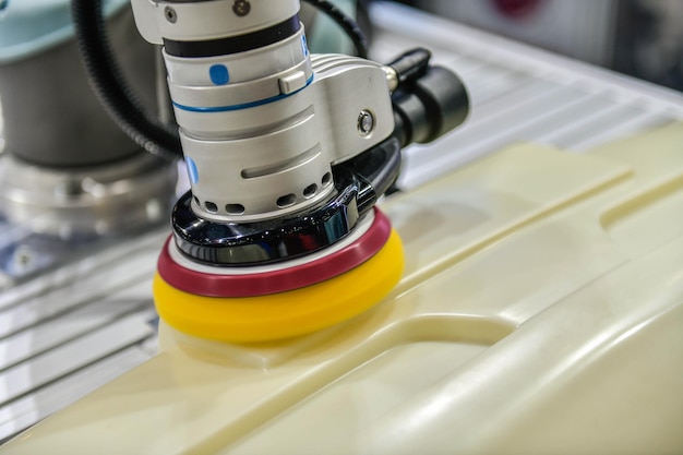 Robotic arm polishing the automotive car part in the production line.