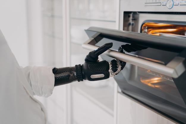 Robotic cyber hand of handicapped person is opening oven at kitchen and going to bake