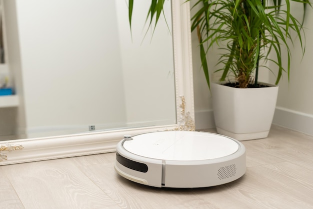 Robotic drone vacuum cleaner on laminate wood floor smart cleaning technology.