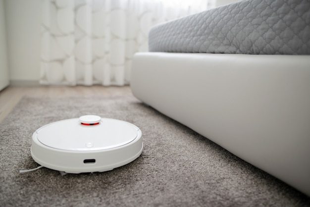 Robotic vacuum cleaner cleaning the room. Robotic vacuum cleaner working on carpet. Smart cleaning technology.