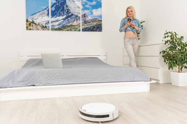 Robotic vacuum cleaner cleaning the room while woman resting.