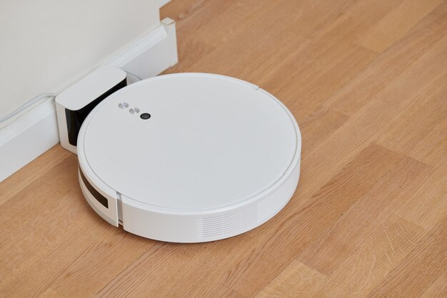 Robotic vacuum cleaner on a laminated wooden floor Smart floor cleaning technology Charging dock station Concept
