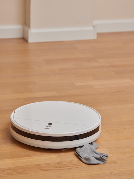 Robotic vacuum cleaner performs cleaning of the room where socks laying on the floor Smart cleaning technology