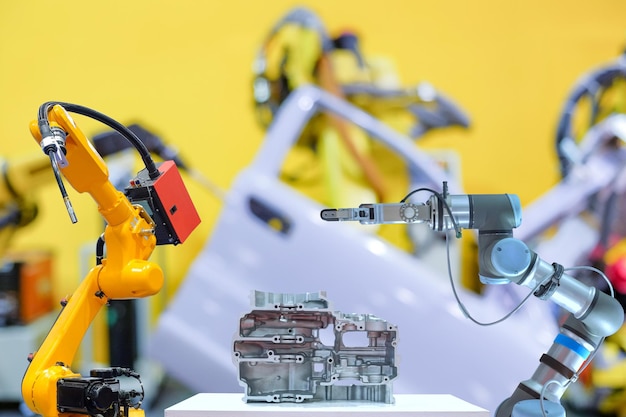 Robotic welding and gripping robot working with metal part on blurred smart car factory background