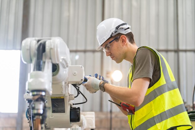 Инженер-робототехник работает над обслуживанием современной роботизированной руки на заводском складе