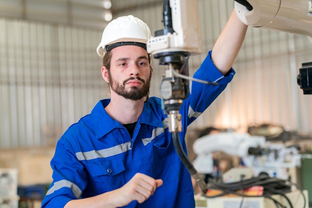 Robotics engineer working on maintenance of modern robotic arm in factory warehouse