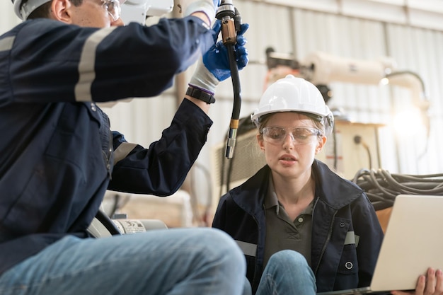 Robotics engineer working on maintenance of modern robotic arm in factory warehouse