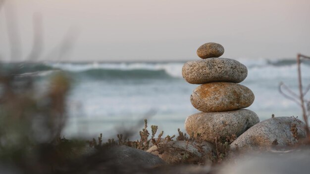 Rock balancing on pebble beach pyramid stacks of stones ocean coast sea water