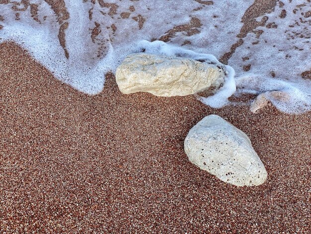 Foto una roccia sulla spiaggia è circondata dall'acqua.