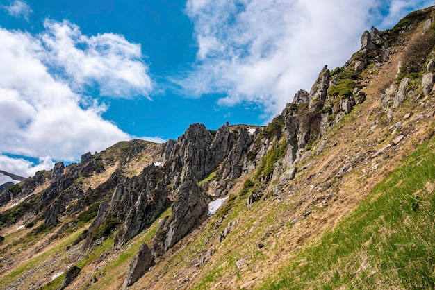 Rock cliff covered with moss over steep slope against cloudy sky