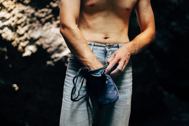 Rock climber applying powder chalk magnesium to his hands before climbing