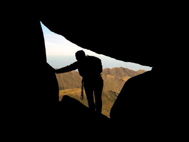 Photo rock climber silhouette inside rocks with mountains