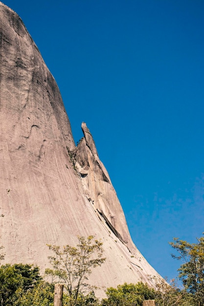 A rock climber stands on a cliff in the mountains.