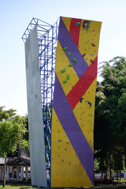 Foto una parete da arrampicata su roccia con uno striscione viola e giallo che dice 