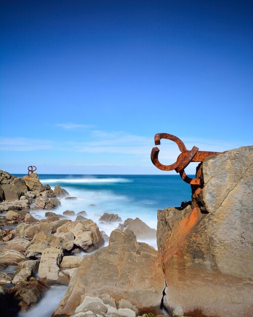 Rock formation on beach against clear blue sky