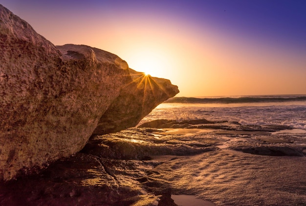 Photo rock formation on beach against sky during sunset