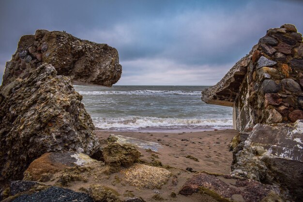 Rock formation on beach against sky