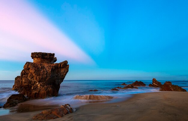 Rock formation on beach against sky