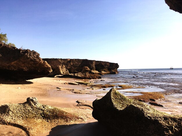 Rock formation on beach against sky