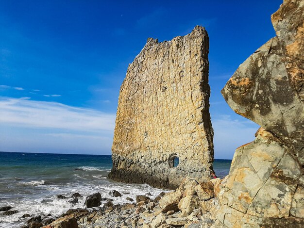 Rock formation on beach against sky