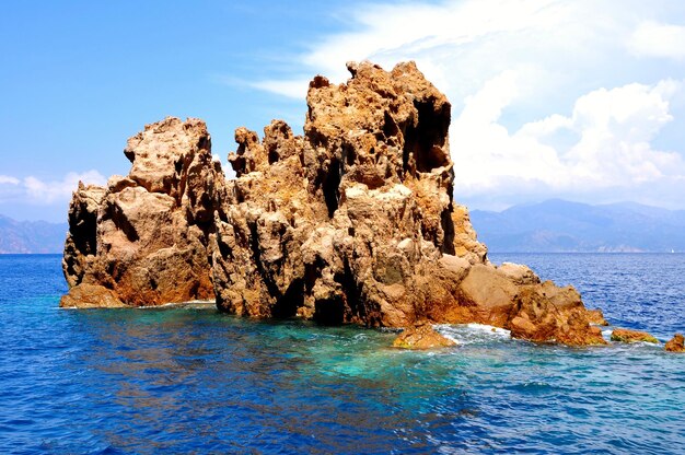 Rock formation by sea against sky