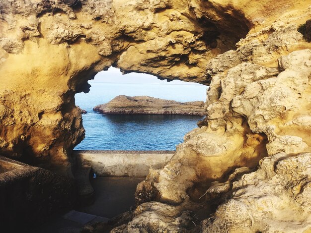 Rock formation by sea against sky