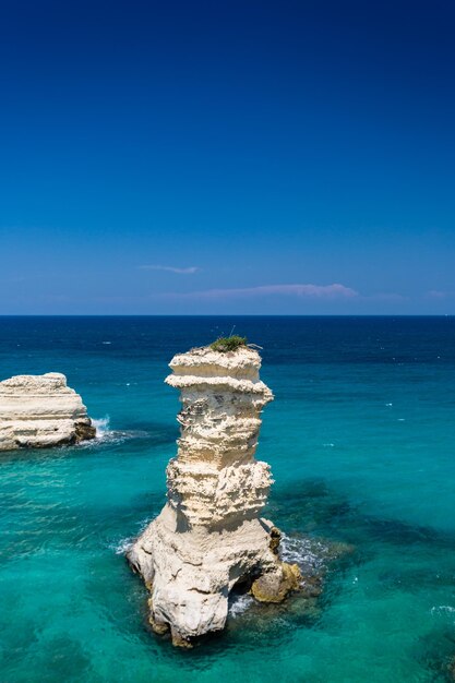 Rock formation in sea against blue sky