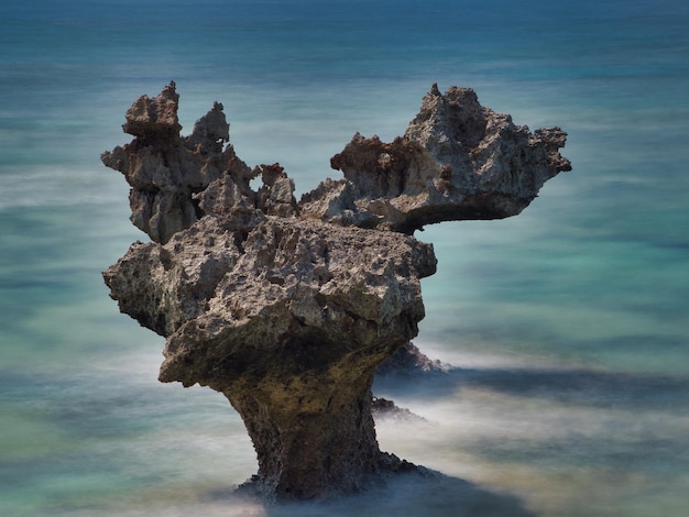 Rock formation in sea against sky