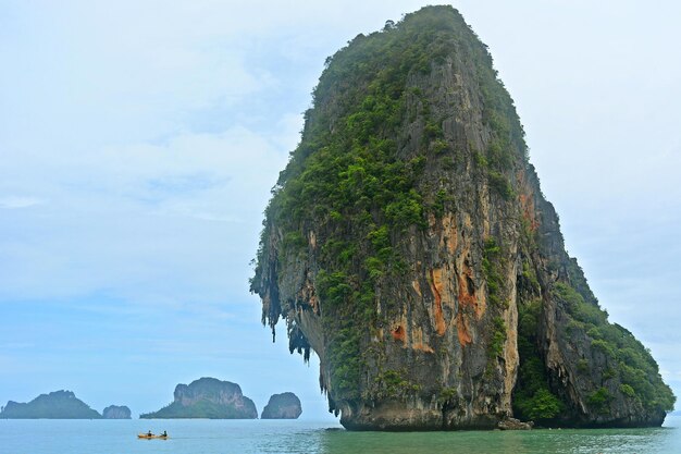 Rock formation in sea at krabi against sky