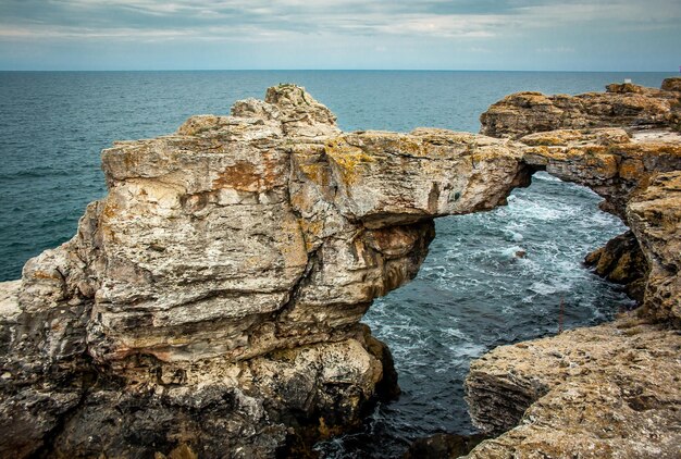 Rock formation on sea shore against sky