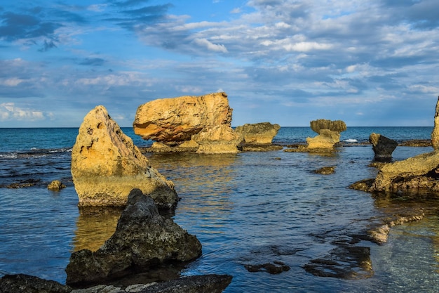 A rock formation in the water with the sun shining on it