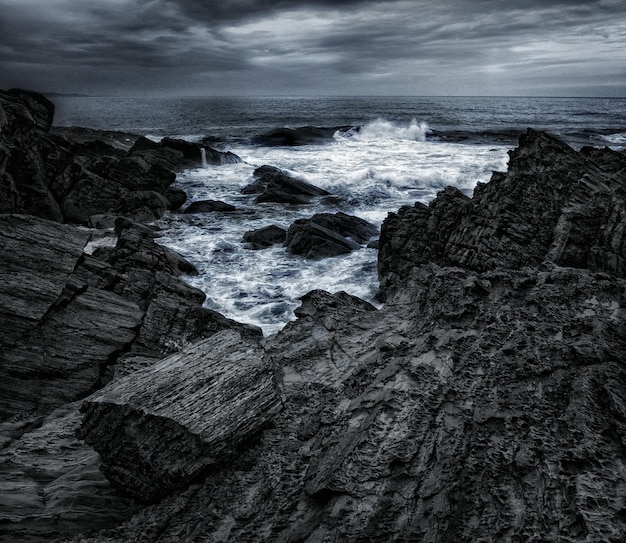 Foto formazioni rocciose sulla spiaggia contro un cielo nuvoloso