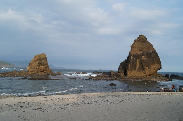 Rock formations on beach against sky