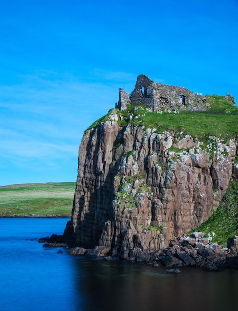 Rock formations by sea against blue sky