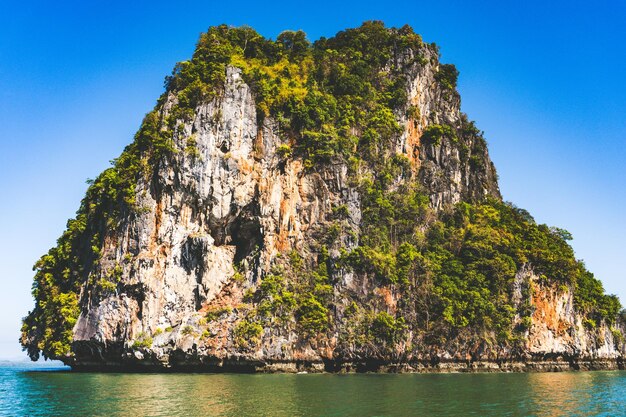 Rock formations by sea against clear blue sky