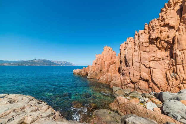 Rock formations by sea against clear blue sky