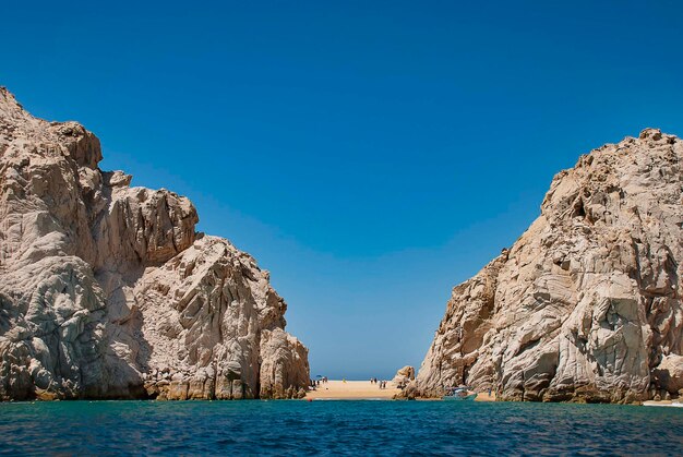 Rock formations by sea against clear blue sky